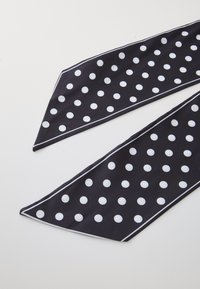 Écharpe noire avec des pois blancs et un fin liseré blanc, présentation d'un design long et étroit. Le matériau semble lisse et doux.