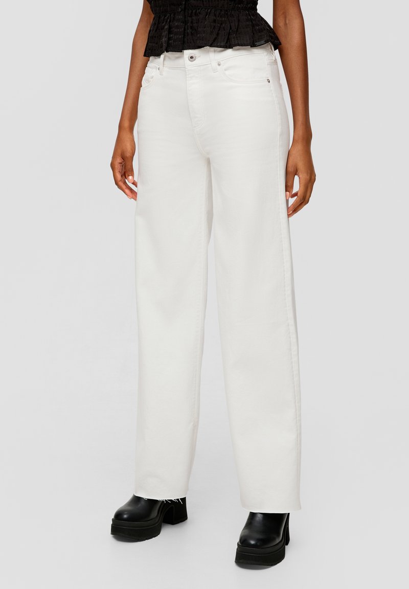 Witte wijde jeans met een hoge taille, gemaakt van denim. Voorzien van voorzakken en subtiele stiksels. Draagt met zwarte platformlaarzen.