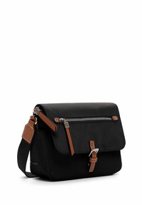 Kompakte schwarze Umhängetasche mit braunen Lederriemen-Akzenten, vorderer Reißverschlusstasche und silberner Schnallenverschluss vor weißem Hintergrund.