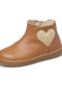 Brun läderankelsk boot med elastisk sidopanel, utrustad med en guldig hjärtapatch och en gummisula. Sömsdetaljer längs tån och sidorna.