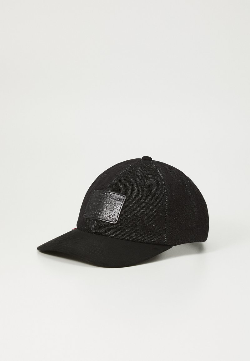 Zwarte pet met een gebogen klep, gemaakt van een gestructureerde stof, met een glanzende zwarte logopatch aan de voorkant en gestikte details op de panelen.