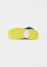 Semelle de chaussure de sport avec un design robuste, équipée d'une semelle extérieure en caoutchouc jaune vif, d'un intercalaire noir et de détails supérieurs en bleu et gris.