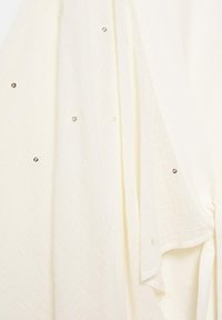 Cream-colored textured fabric with small scattered silver sequins and soft draping.