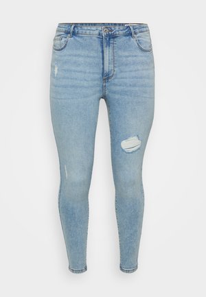 Jeans skinny de denim azul claro apresentam uma cintura alta, bolsos frontais e um joelho desgastado com a borda desfiada. Textura suave, ajuste afunilado.