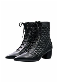 Botas de tobillo negras con textura acolchada, puntera afilada y ojetes dorados. Presentan un diseño con cordones y un tacón bajo cuadrado.