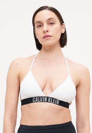 Haut de bikini triangle blanc à côtes avec des fines bretelles, doté d'une bande élastique noire avec "CALVIN KLEIN" en lettres blanches.