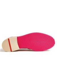 Suola della scarpa con un fondo in gomma rosa rigata, un accento bianco vicino al tallone e una parte superiore di colore crema uniforme.