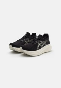 Des chaussures de sport noires avec une tige en mesh texturé, une semelle intermédiaire blanc cassé contrastante et des détails réfléchissants sur les côtés.