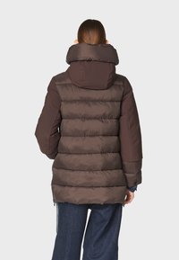 Chaqueta acolchada marrón con alto cuello, que presenta un diseño acolchado, puños elásticos y un dobladillo trasero más largo para mayor cobertura.