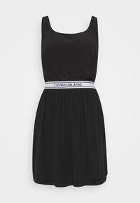 Svart ärmlös klänning med en samlad midja och ett elastiskt band från Calvin Klein Jeans runt midjan, visad mot en vit bakgrund.