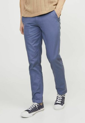 Chinos de algodón azul con corte slim, que cuentan con bolsillos laterales y una textura suave, combinados con zapatillas casuales navy.