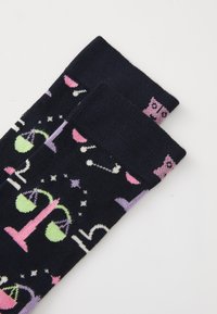 Chaussettes navy avec un mélange de motifs colorés, y compris des écailles, des étoiles et des os, avec une texture douce et élastique et des accents roses.