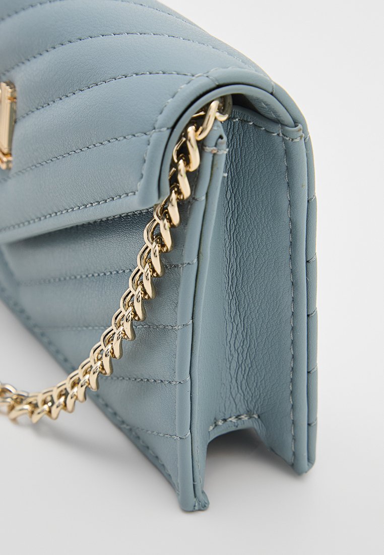 Bolso de mano de cuero azul con textura acolchada, cadena dorada y forma estructurada. Presenta detalles cosidos y un acabado suave.