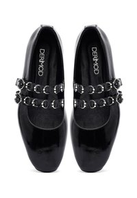 Scarpe in vernice nera con punta arrotondata, caratterizzate da due cinturini decorati con accessori metallici circolari. Texture liscia e design elegante.