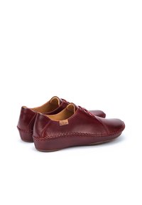 Zapatos de cuero rojo con un acabado suave, punta redondeada y detalles cosidos a mano a lo largo de los bordes. Forro interior color marrón claro.
