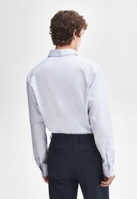 Lichtblauwe overhemden met lange mouwen, van katoen, met een standaard kraag en een gladde textuur, gedragen met donkere broeken.