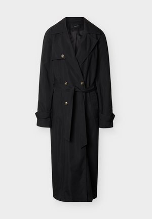 Μαύρο μακρύ παλτό τύπου τρανς με πλατιούς γιακάδες, διπλή σειρά κουμπιών, ζώνη στη μέση και μανίκια με μπάσκα, πάνω σε λευκό φόντο.