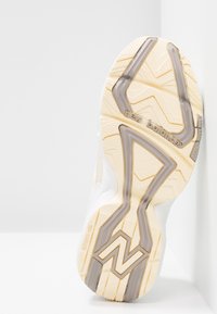 Semelle de chaussure de sport blanche avec un motif texturé en zigzag. Présente des accents gris clair et un logo "New Balance" argenté. Fini lisse et durable.