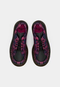 Lace-up sneakers with a black leather toe and purple plaid fabric upper. Features contrasting yellow stitching and a rounded outsole.