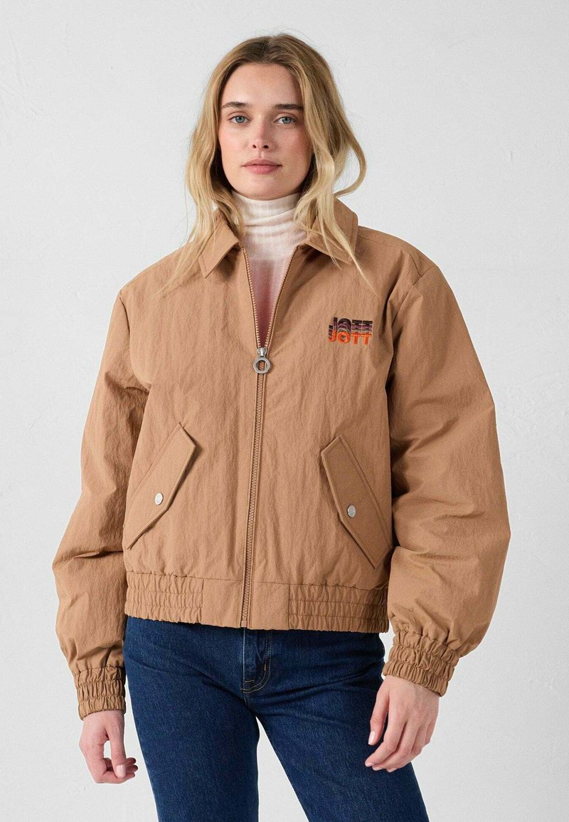 Giacca bomber in nylon marrone con zip frontale, polsini elasticizzati, tasche laterali e logo ricamato in arancione e blu navy. Tessuto liscio e vestibilità corta.