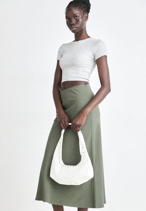 Pilka juostuota trumpa palaidinė ir alyvuogių žalios spalvos aukšto liemens sijonas. Modelis laiko baltą petį krepšį su išpjovomis. Paprastas dizainas, prigludusi siluetas.