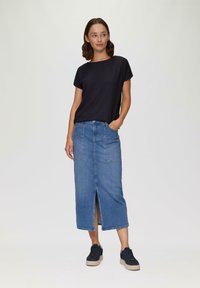 Czarny, fakturowany top z krótkim rękawem połączony z midi spódnicą dżinsową z rozcięciem z przodu i dwiema kieszeniami, noszony z czarnymi trampkami na platformie.