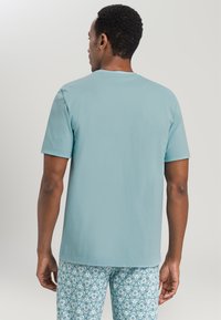 T-shirt azzurro chiaro a maniche corte realizzato in morbido cotone, con scollatura rotonda e vestibilità comoda. Indossato con pantaloni del pigiama stampati.