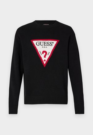 Maglione nero lavorato a maglia con un grande triangolo rosso e testo bianco che recita "GUESS® U.S.A." e un motivo centrale a punto interrogativo. Polsini e orlo a costine.