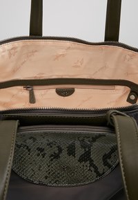 Torebka oliwkowozielona z teksturowanym klapą z wężowym wzorem i gładkim wykończeniem. Wnętrze z jasnopomarańczową podszewką i kieszenią na zamek.