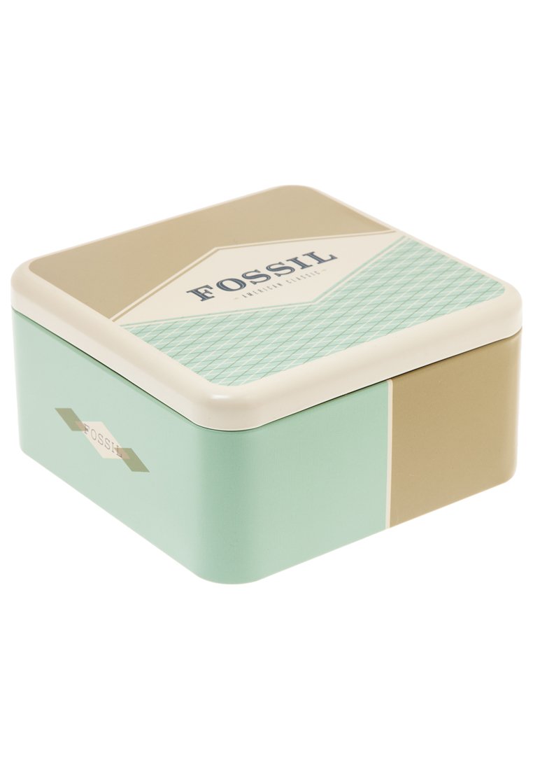 Boîte en métal carrée Fossil avec un corps vert menthe, un couvercle beige et un motif géométrique. Présente un logo et des accents décoratifs sur les côtés.