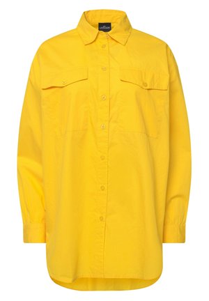 Camisa amarilla de botones, hecha de tejido ligero, con mangas largas, dos bolsillos en el pecho y un cuello. Textura suave y corte relajado.