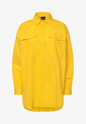 Camisa amarilla de botones, hecha de tejido ligero, con mangas largas, dos bolsillos en el pecho y un cuello. Textura suave y corte relajado.