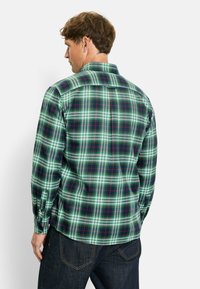 Grünes und marineblaues Karohemd mit roten Akzenten, ausgestattet mit einem klassischen Kragen und knöpfbaren Manschetten. Hergestellt aus leichtem Stoff, der ein kariertes Muster zeigt.