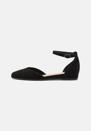Ballerine in suede nero con cinturino alla caviglia, punta affilata, tacco basso e lati aperti. Design semplice con una sola fascia regolabile.