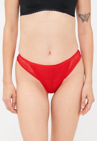 Bikini in pizzo rosso con un design a motivi, dotato di una vita liscia e dettagli a taglio sui lati.