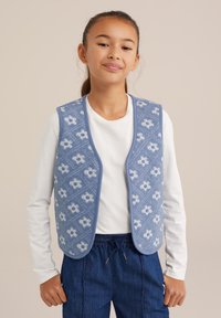 Blå stickad väst med ett blommönster, rundade kanter och en texturerad design. Bärs över en vit långärmad skjorta med blå byxor.