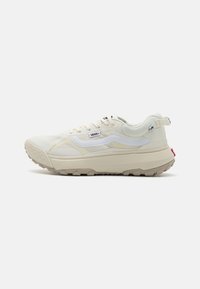 White sneakers with a textured cream upper, a chunky sole, and a contrasting red accent on the back. Features a mesh design and logo.