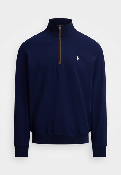 Marineblå langærmet pullover med kvart-lynlås og hvid broderet hest og rytter-logo på venstre bryst.