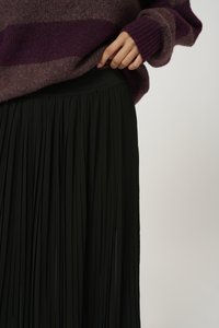 Mustraleheline must seelik, millel on struktuurne ja voolav disain, koos marooni triibulise kampsuniga, millel on soonikuotsad.