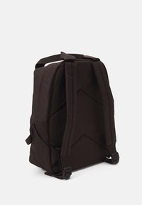 Mochila de tela negra con un diseño estructurado, que presenta lados acolchados, correas ajustables y un patrón geométrico en la superficie.
