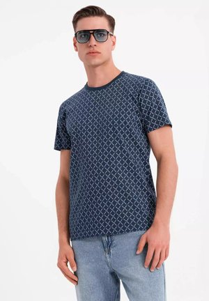 Camiseta de manga corta azul marino con patrón de diamantes blancos, cuello redondo y tela suave. Modelo con gafas de sol y jeans de color azul claro.