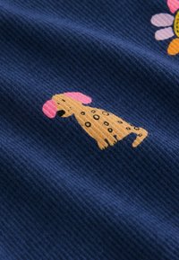 Námořnická žebrovaná látka s kresleným bodem psa v barvách béžová a růžová, s černými skvrnami. Jsou zde barevné květinové akcenty.