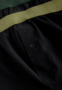 Melni auduma šorti ar teksturētu olīvzaļo elastīgo jostasvietu, vienas pogas aizdari un gludu tekstūru visā virsmā.