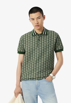 Polo vert à motifs avec des rayures blanches sur le col. Fabriqué en tissu respirant, avec un design géométrique et un accent logo.