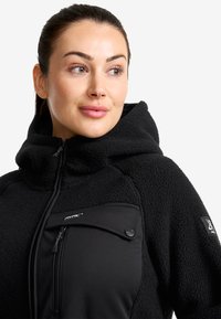 Svart fleecetröja med huva, med en zip-försluten bröstficka, knappdetalj, strukturerad tyg och en slät frampanel.