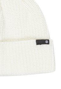 Biała dziana czapka beanie o prążkowanej fakturze i złożonym mankiecie, z małą czarną metką z boku.
