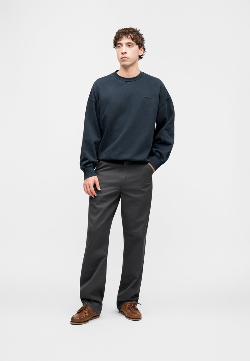 Felpa blu scuro con scollo arrotondato, vestibilità comoda. Pantaloni grigi con gambe dritte. Mocassini marroni con lacci. Design semplice e minimalista.