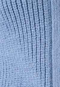 Acercamiento a una suave tela de punto azul claro con textura de ribete vertical y fibras de hilo visibles.