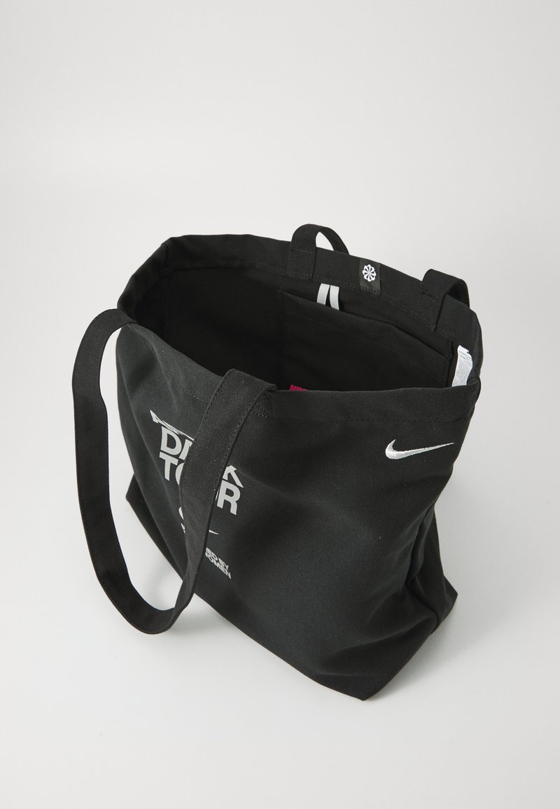 Sac fourre-tout en toile noire avec des poignées noires doubles, arborant du texte de marque blanc et un petit logo blanc à l'intérieur. Design simple et spacieux.