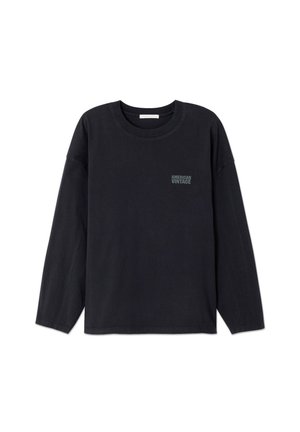 Schwarzes Langarmshirt mit Rundhalsausschnitt und kleinem "American Vintage"-Logo auf der linken Brust, dargestellt vor einem schlichten weißen Hintergrund.